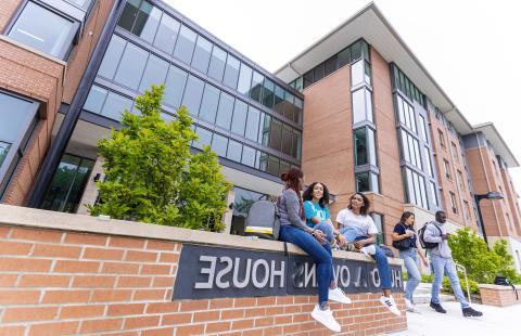 学生 sitting and talking in front of Hugo Owens residence hall